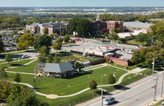 Top building view surroundings looking at a public green area, gas station, and other buildings farther away.