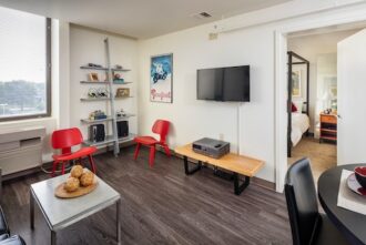 A living room decorated with red chairs, fully furnished and with biew of entrance to bedroom