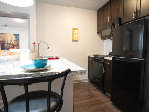 10th floor kitchen appliances: stove, refrigerator, cabinets, marble countertop with wood floors.